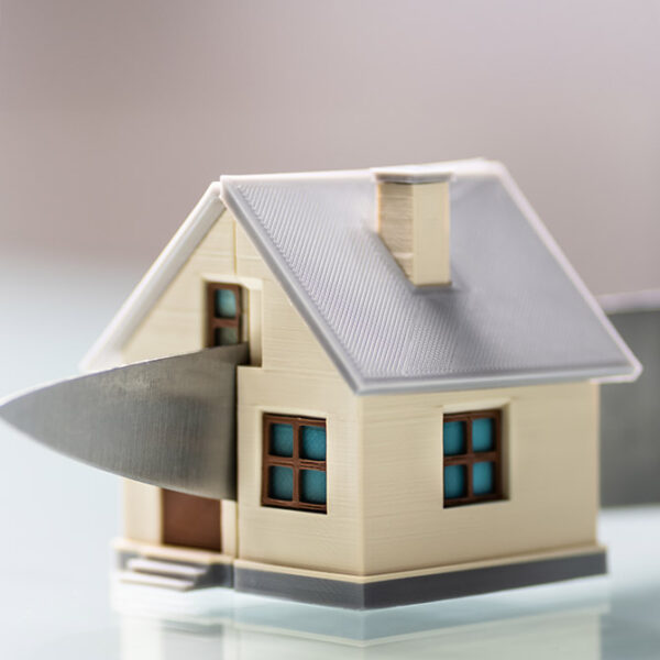 Picture of a model of a house being sliced in half with a knife - Depicting the sharing of a property TLATA Dispute