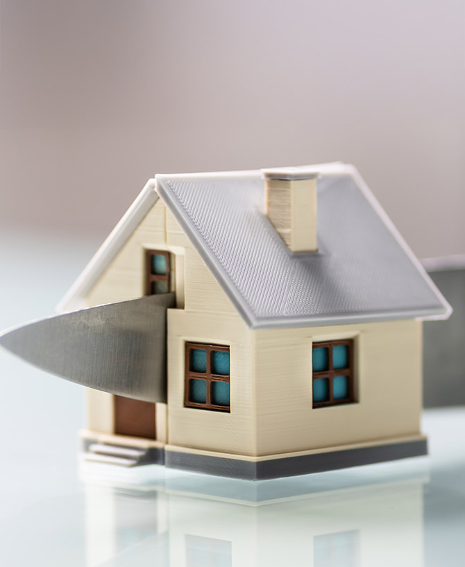 Picture of a model of a house being sliced in half with a knife - Depicting the sharing of a property TLATA Dispute